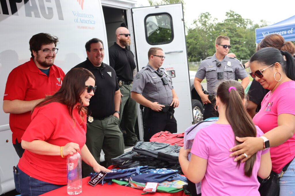 Safe Return staff and law enforcement hand out backpacks to clients.